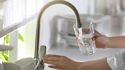 closeup of a person pouring drinking water from tap in modern kitchen