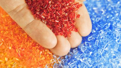 A hand grasping a collection of bright plastic beads, illustrating a spectrum of colors and playful designs.