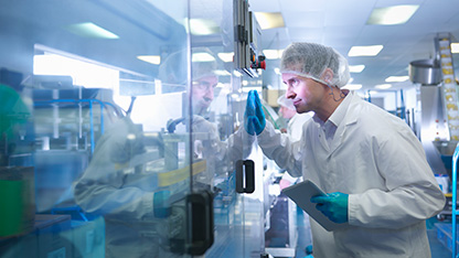 Worker inspecting tablets as they are put into packaging in pharmaceutical factory